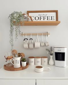 a kitchen counter with coffee cups and mugs hanging on the wall next to a microwave