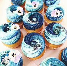 cupcakes with blue frosting and white flowers on top are arranged in a spiral pattern