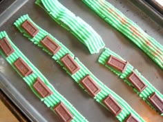 some green and brown cookies are on a baking sheet with chocolate bars in them, ready to be baked