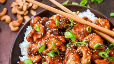 chicken with sesame seeds and green onions served on rice in a brown bowl next to chopsticks