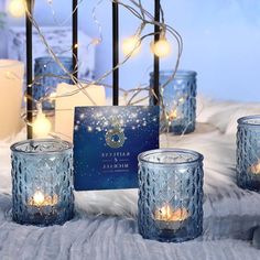 blue glass candles are sitting on a white furnishing next to a greeting card