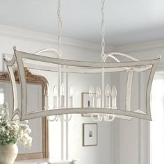 a chandelier hanging from the ceiling in a dining room with white walls and furniture