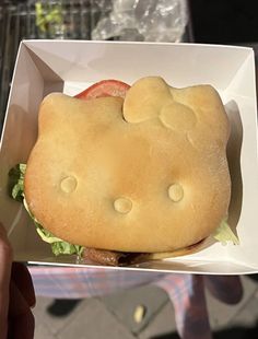 a hello kitty sandwich with lettuce and tomato in a white paper box on a table