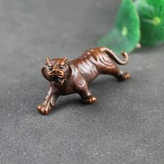 a small figurine of a cat on the ground next to a green plant