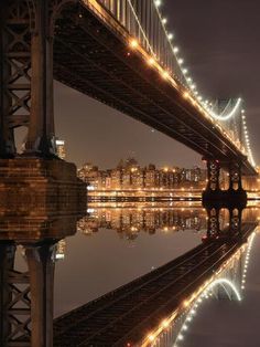 the bridge is lit up at night and reflecting in the water with lights on it