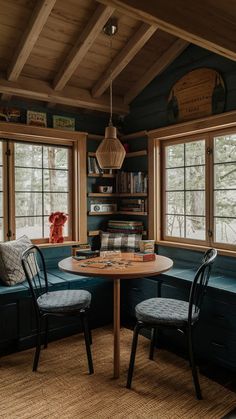 a table and two chairs in a room with wooden walls, windows, and rugs on the floor