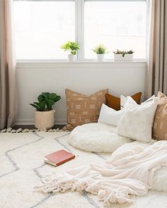 a bed with pillows and blankets on top of it next to a potted plant