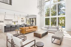 a living room filled with furniture next to a large open floor plan and lots of windows