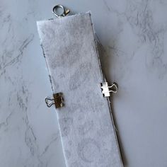 a white towel with two silver rings on it sitting on a marble counter top next to a pair of scissors