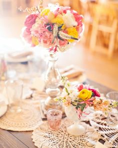 a table topped with lots of flowers on top of a doily covered dining room table