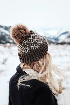 a woman with blonde hair wearing a brown and white pom - pom hat