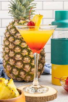 a pineapple drink in a glass next to other fruit