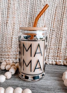 a glass jar with an orange straw sticking out of it sitting on a table next to shells