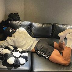 a man laying on top of a black leather couch next to a stuffed animal bear