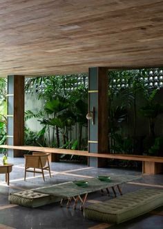 a room filled with lots of green plants and wooden benches in front of large windows