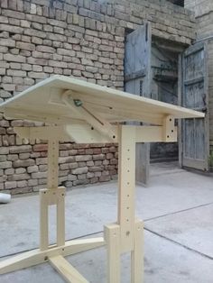 a wooden table sitting on top of a cement floor next to a brick wall and door