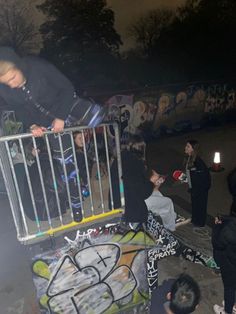 a group of young men standing around a metal barricade with graffiti on it