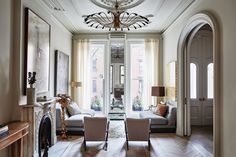 a living room filled with furniture and a fire place under a chandelier in front of a fireplace