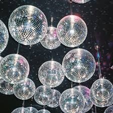 many disco balls hanging from the ceiling in front of a black background with white lights