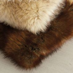 a brown and white furry animal laying on top of a bed next to a pillow