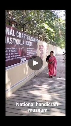 a woman in a pink sari is walking down the sidewalk near a sign that says national handicraf museum