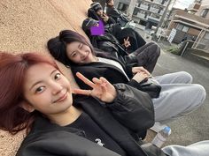 two young women laying on the ground making peace signs with their hands in front of them