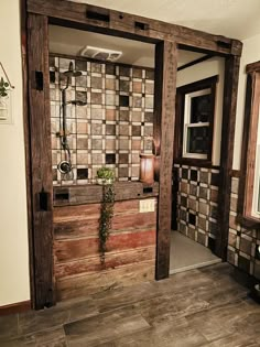 an open door leading to a bathroom with tiled walls and wood floors, along with potted plants