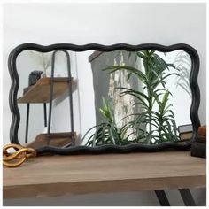 a mirror sitting on top of a wooden table next to a potted green plant