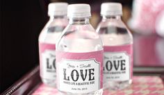 three bottles of love water are sitting on a table with pink and white patterns around them