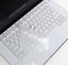 an apple laptop computer sitting on top of a white table next to a black keyboard