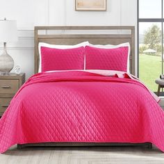 a bright pink quilted bed in a bedroom