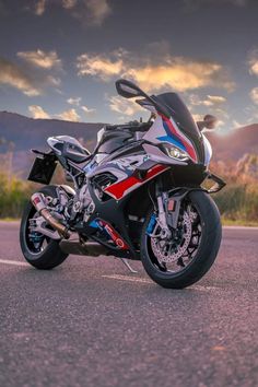 the motorcycle is parked on the side of the road with mountains in the back ground