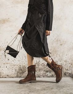 a woman in brown boots is walking down the street with a black bag and purse