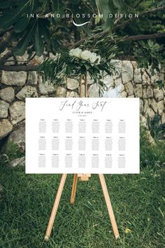 a wedding seating chart on a easel in the grass with flowers and greenery