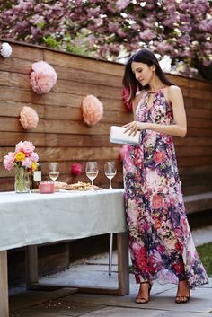 a woman standing in front of a table with wine glasses and flowers on the table