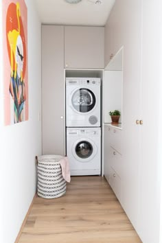 a washer and dryer are in the corner of this small room with wood flooring