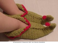 a pair of crocheted slippers with red trims on the toes and feet