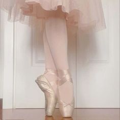 a ballerina's feet in ballet shoes standing on the floor