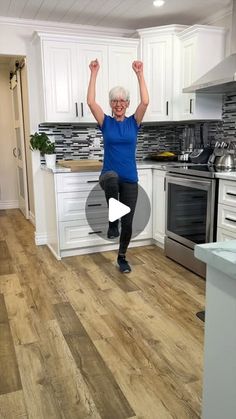 an older woman jumping in the kitchen with her hands up