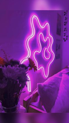 a vase with flowers sitting in front of a neon sign