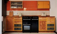 a kitchen with an oven, cabinets and counter tops in orange and grey colors on the walls