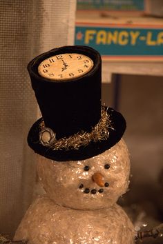 a snowman wearing a top hat with a clock on it