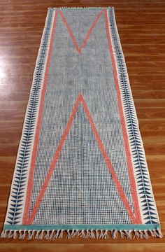 a blue and red rug with fringes on top of a wooden floor in a room