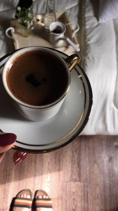 a cup of coffee on a saucer in someone's hand