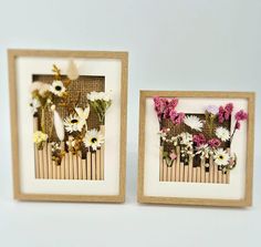 two framed pictures with flowers on them sitting next to each other in front of a white wall