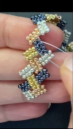 someone is holding some small beads in their hand and they are making something out of them