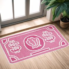 a pink door mat with white designs on the floor next to a potted plant