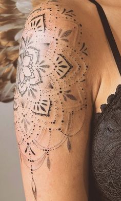 a woman's arm with an intricate tattoo design on the back of her shoulder