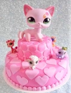 a pink cake with littlest pet shop figurines on top