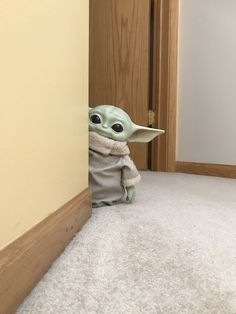 a baby yoda doll is peeking out from behind the corner of a door way